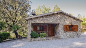 A stone house with a wooden door and windows, surrounded by trees and gravel. - Stone house nº5 for 4 people, Batan Rio Tus (Yeste)
