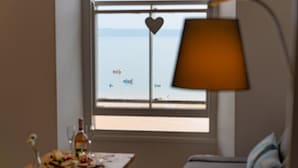 Ein Zimmer mit Meerblick, ein Tisch mit Speisen und Getränken sowie eine Lampe.