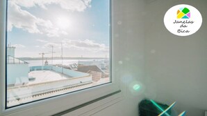 Una stanza con un'ampia finestra che si affaccia su una zona costiera con edifici e un tratto d'acqua.