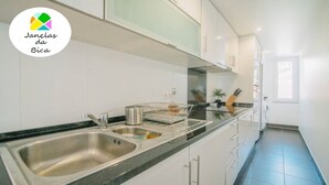 Una cucina moderna con pensili bianchi, un lavello in acciaio inossidabile e un piano di lavoro nero.
