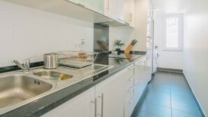 Een moderne keuken met witte kasten, een roestvrijstalen spoelbak en een zwart aanrecht.