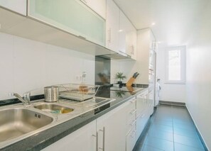 Une cuisine moderne avec des meubles blancs, un évier en acier inoxydable et un plan de travail noir.