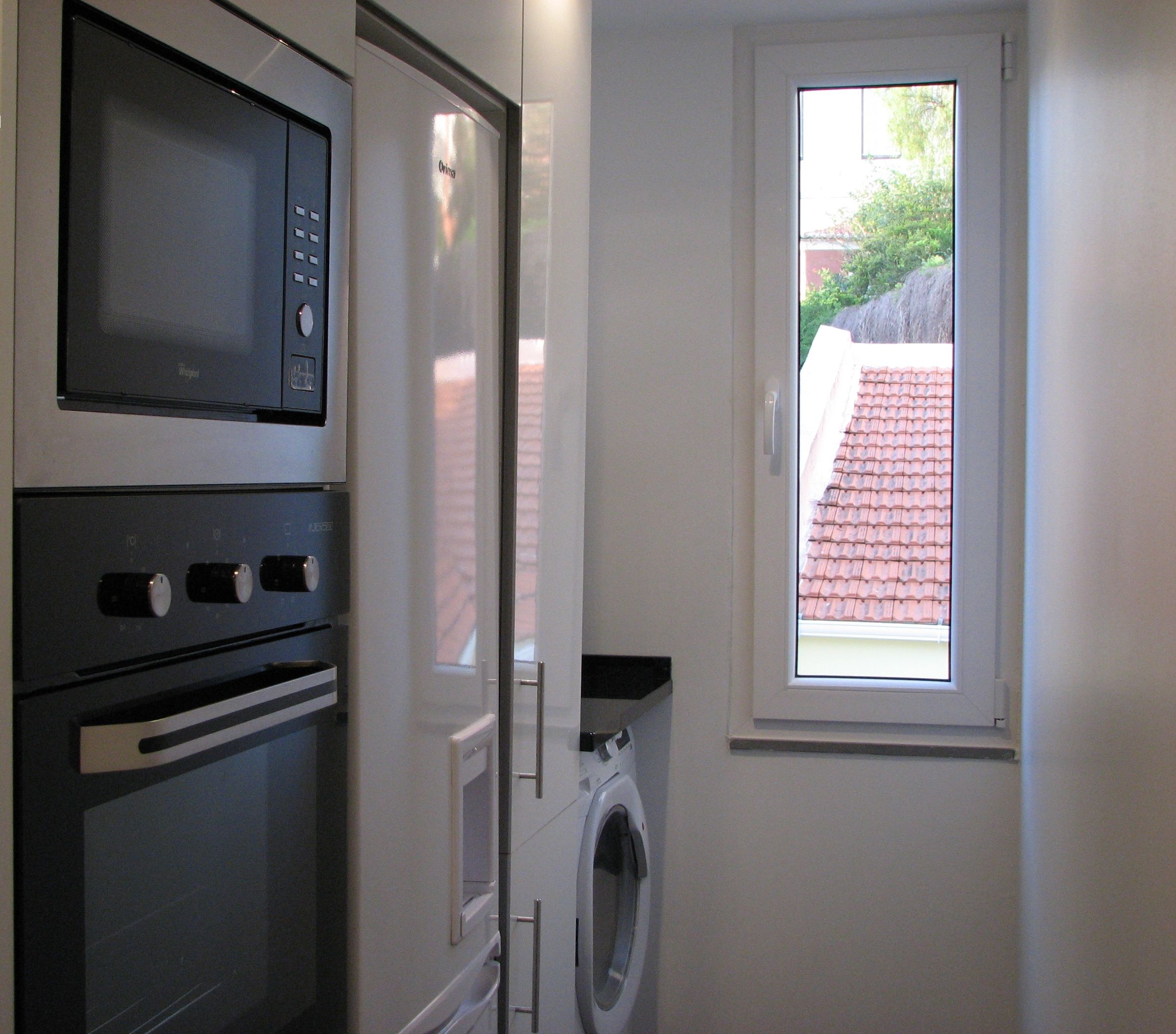 A compact kitchen with a microwave, oven, and washing machine.