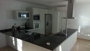 A modern kitchen with a central island, built-in oven, microwave, and refrigerator. - Recent house with lagoon views 100 meters from the beach (LAGOA DE ALBUFEIRA)