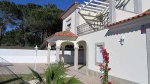 A two-story house with a balcony, a white fence, and a garden with plants and flowers. - Recent house with lagoon views 100 meters from the beach (LAGOA DE ALBUFEIRA)