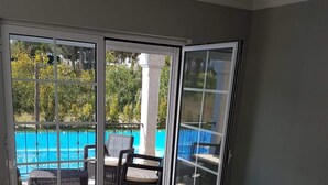 A room with a large table and chairs, a sliding glass door leading to a pool area. - Recent house with lagoon views 100 meters from the beach (LAGOA DE ALBUFEIRA)