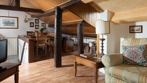 Un ampio loft con travi a vista in legno, un'area pranzo, un divano e una televisione.