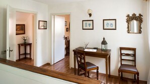 Zona pranzo con tavolo e sedie in legno, un piccolo tavolino con un vaso e quadri appesi al muro.
