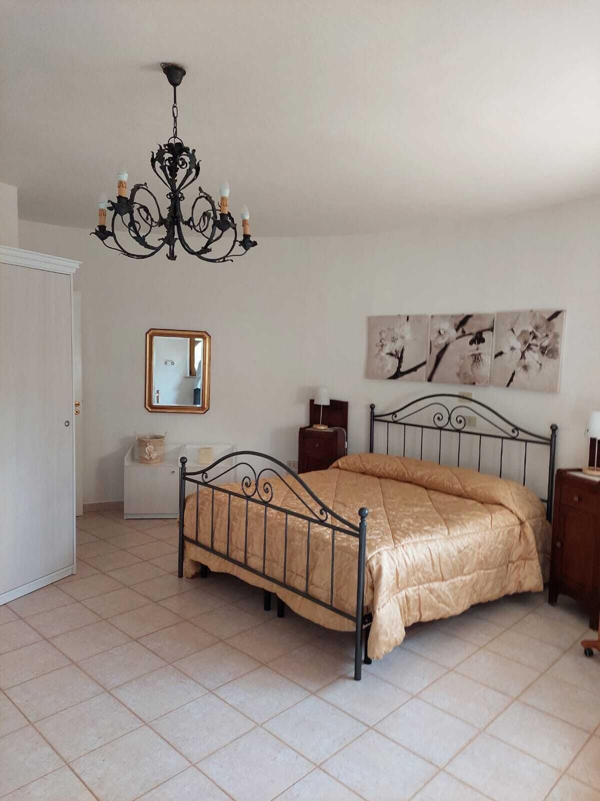 Ein Schlafzimmer mit einem Bett, einer Chandelier, einem Spiegel und Kunstwerken an der Wand.