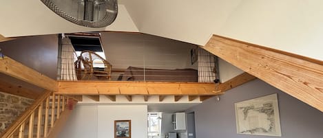 A loft-style living space with a dining area, a kitchen in the background, and a staircase leading to an upper level.