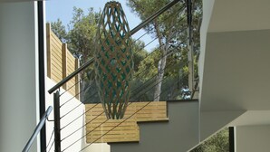 Una escalera moderna con barandilla de vidrio que conduce a una habitación con vistas a un jardín de cactus.