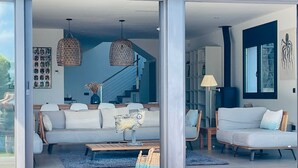Una sala de estar moderna con un sofá, sillas y una mesa de centro. Una escalera conduce a un nivel superior.