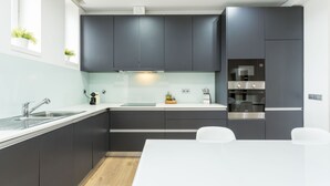 A modern kitchen with dark cabinets, a white countertop, and a built-in oven. - Feel Porto Downtown Heaven (Oporto)