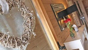 Ein Holzinterieur mit einem herzförmigen Spiegel, einer Vase mit roten Blumen und einem kleinen Tisch mit einer Flasche.