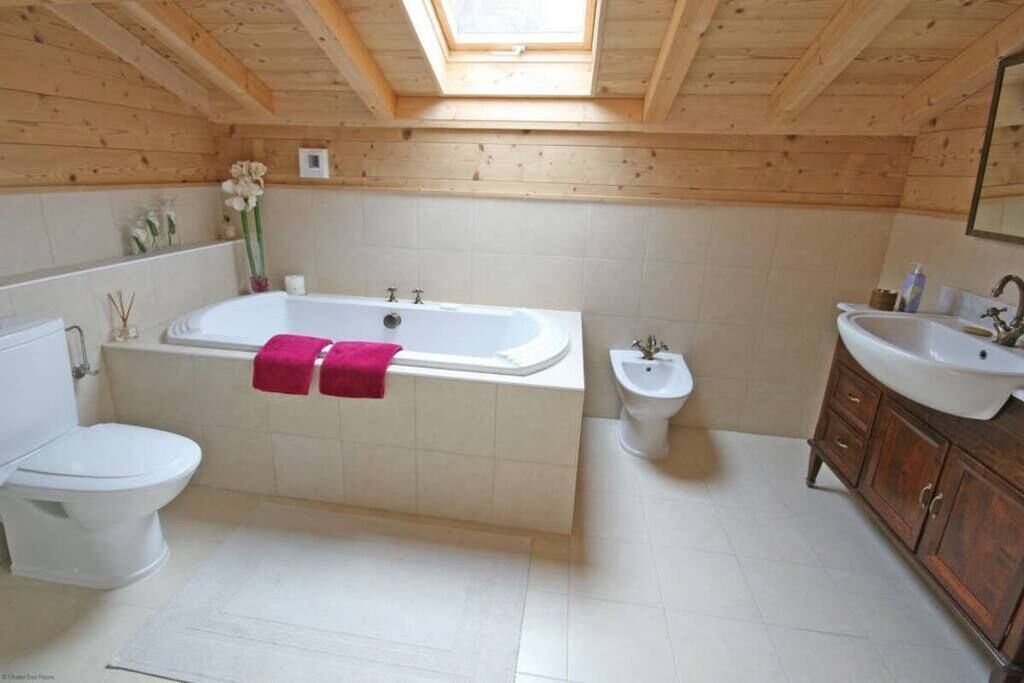 A bathroom with a wooden ceiling, a bathtub, a toilet, a bidet, and a sink.