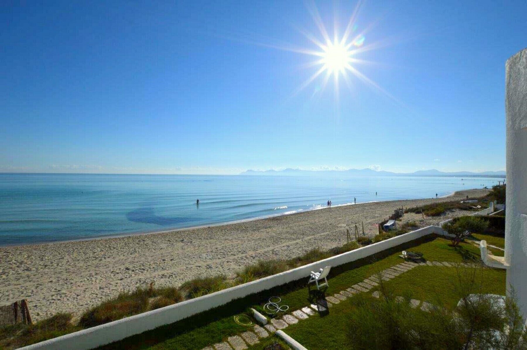 A beach with a clear view of the ocean and distant mountains.