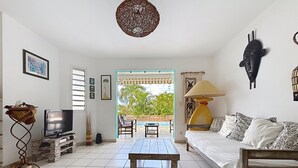 A living room with a sofa, a coffee table, a TV on a stand, and a view of the outdoors. - House / Villa - Sainte luce (sainte luce)