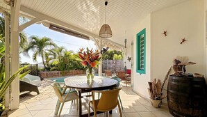 A covered patio with a round table, chairs, and a decorative vase. - House / Villa - Sainte luce (sainte luce)