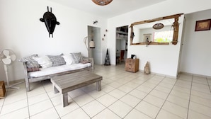 A living room with a sofa, a wooden coffee table, a fan, and a mirror on the wall. - House / Villa - Sainte luce (sainte luce)