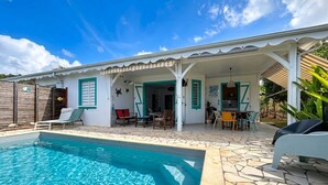 A poolside area with a clear pool, outdoor seating, and a covered patio. - House / Villa - Sainte luce (sainte luce)