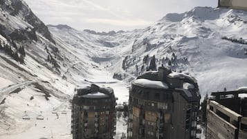 Een met sneeuw bedekte berg met een skilift en een gebouw met meerdere verdiepingen en balkons.