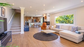A spacious living room with a staircase, a dining area, and a kitchen in the background. - Villa Bahías - with private swimming pool (Bahía Grande)