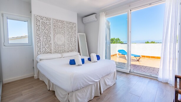 A bedroom with a bed, a window, a sliding glass door to a balcony, and a wall-mounted air conditioner. - Villa Bahías - with private swimming pool (Bahía Grande)