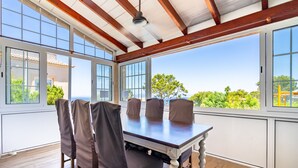 A sunlit room with a large table and chairs, large windows, and a wooden ceiling. - Villa Bahías - with private swimming pool (Bahía Grande)