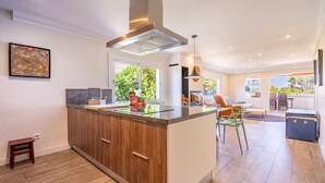 A modern kitchen with a central island, wooden cabinets, and a large window providing natural light. - Villa Bahías - with private swimming pool (Bahía Grande)