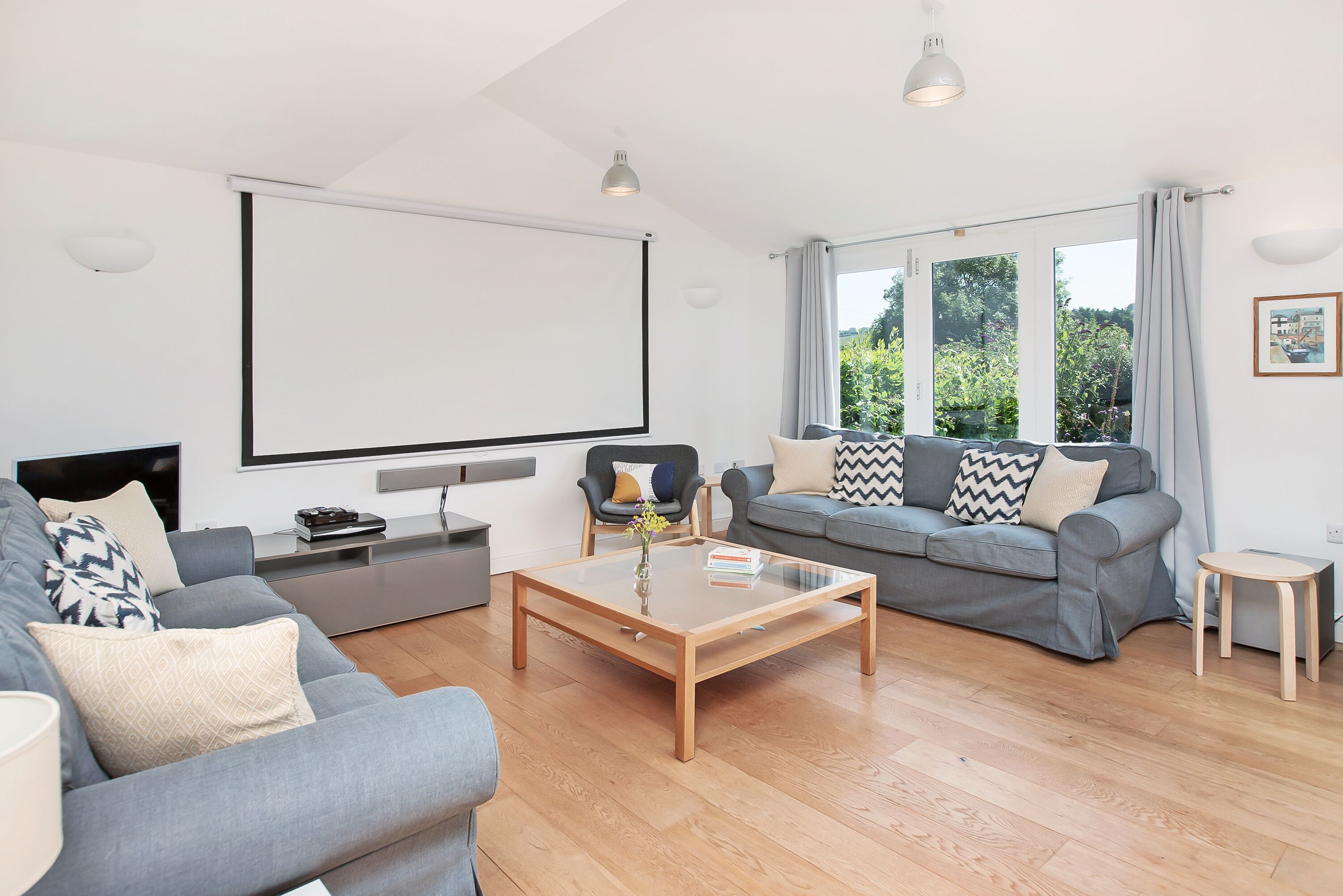 A modern living room with a grey sofa, a wooden coffee table, and a large window with curtains.