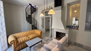 A modern living room with a sofa, armchairs, a coffee table, a fireplace, and a spiral staircase. - Charming apartment in the Old Town of Seville, next to Santa Cruz. (Sevilla)
