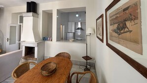 A dining area with a wooden table, wicker chairs, and a fireplace. - Charming apartment in the Old Town of Seville, next to Santa Cruz. (Sevilla)