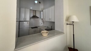 A compact kitchen with white cabinets, a built-in stove, and a hanging light fixture. - Charming apartment in the Old Town of Seville, next to Santa Cruz. (Sevilla)