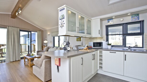 A modern kitchen with white cabinets, a microwave, and a window with blinds. - Luxury 3 bed Lodge In Soar, Salcombe, Devon, Sea & Country views (Salcombe)