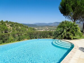 A clear blue swimming pool with a curved edge, surrounded by lush greenery and a view of distant hills and mountains. - Villa With Private Pool And Stunning Views. (Cessenon-Sur-Orb)