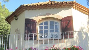 A building with a balcony, a window with shutters, and flower boxes.