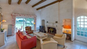 A spacious living room with a fireplace, a television, and a dining area with outdoor views.