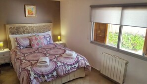Une chambre à coucher avec un lit, des lampes de chevet, un radiateur et une fenêtre avec des stores.