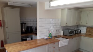 A kitchen with white cabinets, a wooden countertop, a sink, a microwave, and a toaster. - HartHill Grange Bunkhouse - Unique 1850's Rural Country Accommodation (Lydney)