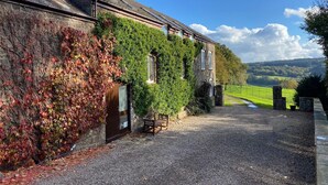 A stone building with ivy-covered walls and a gravel driveway leading to a bench. - HartHill Grange Bunkhouse - Unique 1850's Rural Country Accommodation (Lydney)