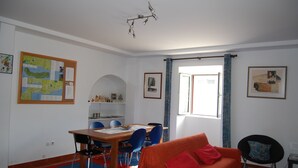 A dining area with a wooden table and blue chairs, a red sofa, and a map on the wall.