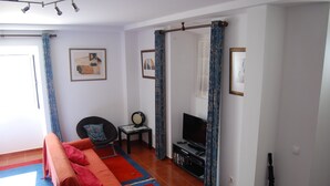 A living room with a sofa, TV, and a small table with a decorative item.