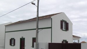 A white building with green trim and a brown gate.