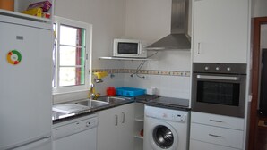 A compact kitchen with a microwave, oven, washing machine, and a sink.