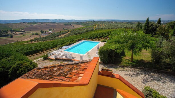 A rooftop pool with a clear view of vineyards and distant hills.