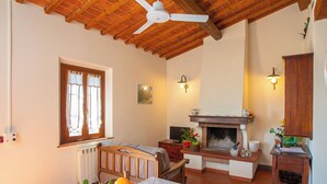 A cozy room with a wooden ceiling, a fireplace, a dining table with fruit, and a television.