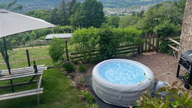Quintal com hidromassagem, mesa de piquenique e vista para uma cidade e colinas.