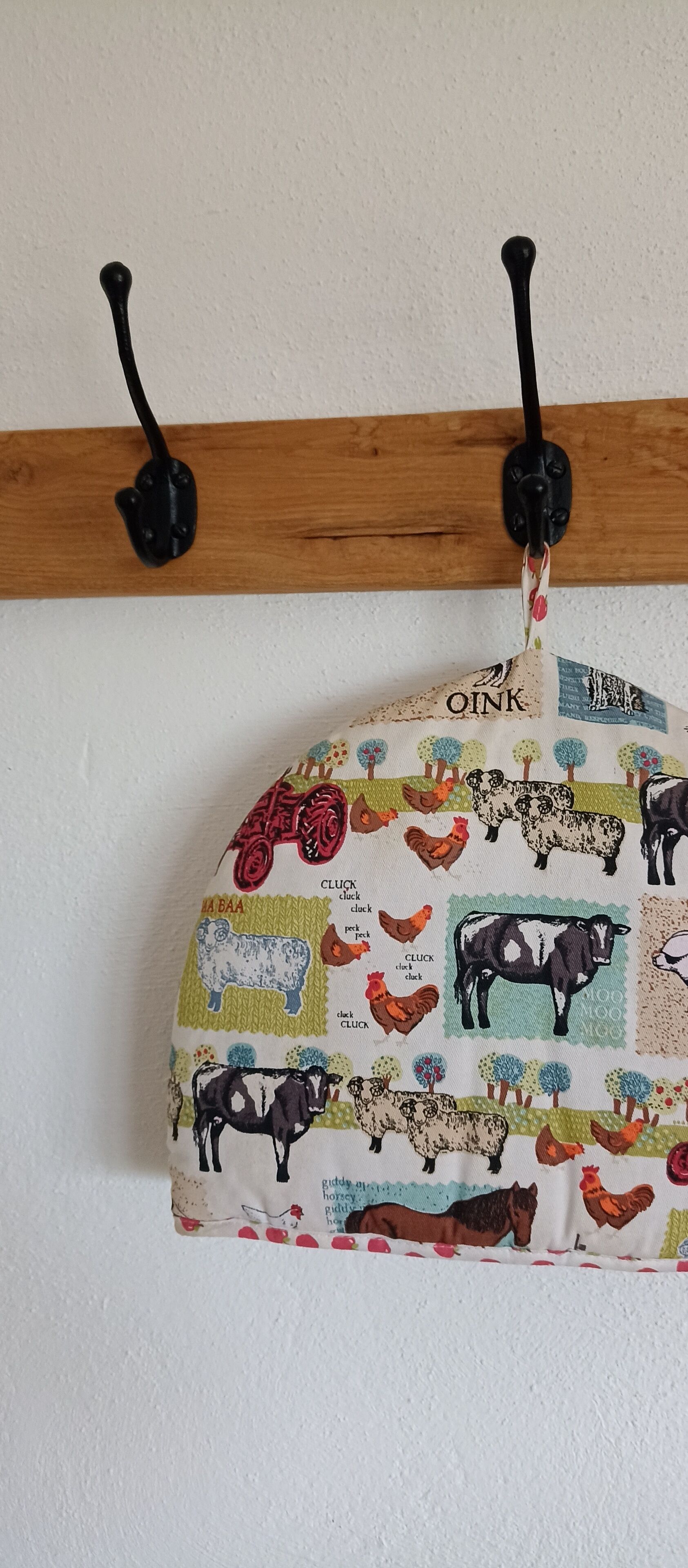 En väggmonterad krok med en dekorativ tygpåse som har motiv av husdjur.