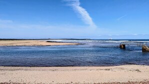 A coastal scene with a sandy beach, calm water, and a bridge. - Beach Chalet With Panoramic Views (Dunbar)