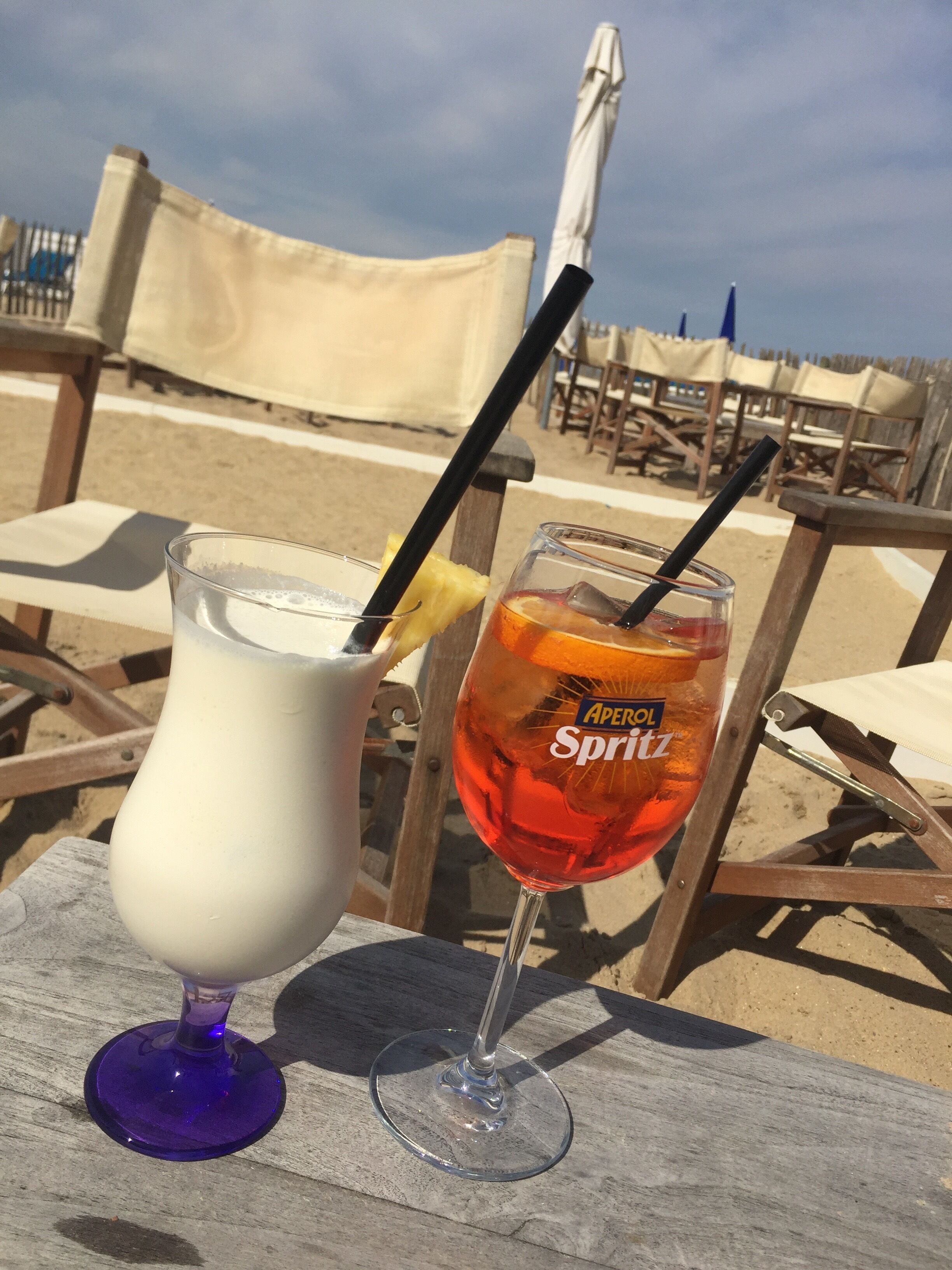 Dos bebidas sobre una mesa de madera en un lugar junto a la playa.
